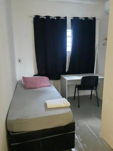 Kleines Zimmer mit einem Bett, einem Schreibtisch und einem Fenster in der Unterkunft Pousada Aeroporto Viracopos Campinas in Viracopos