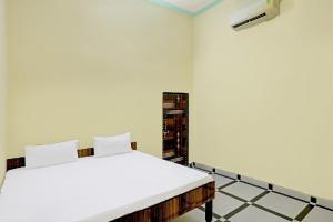Una cama blanca en una habitación con en OYO J.M.D Restaurant &rooms en Jhājhar