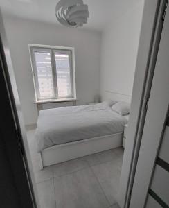 a white bedroom with a bed and a window at Apartament w samym centrum in Warsaw
