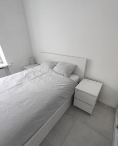 a white bedroom with a bed and two night stands at Apartament w samym centrum in Warsaw