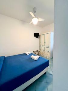 Schlafzimmer mit einem blauen Bett und einem Deckenventilator in der Unterkunft La Giara in Vulcano