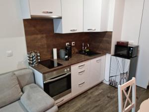 a small kitchen with white cabinets and a microwave at Apartman - Centrum in Bratislava +3 photos