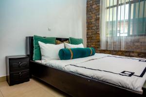 uma cama com almofadas verdes e brancas e uma janela em Ibuye Villa em Nyakinama