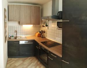cocina con armarios de madera y nevera negra en Hawis Appartement, en Maishofen
