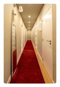 a long hallway with a red carpet and white doors at Quebra Costas House in Coimbra