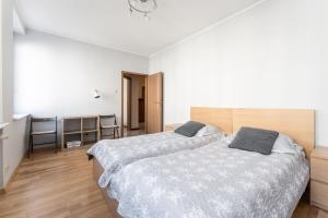 - 2 lits dans une chambre dotée de murs blancs et de parquet dans l'établissement Apartament Świętego Ducha 3234, à Gdańsk