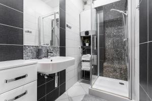 a black and white bathroom with a sink and a shower at Apartament Świętego Ducha 3234 in Gdańsk