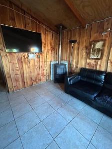salon z czarną skórzaną kanapą i telewizorem w obiekcie •Cabañas Patagonia• w mieście Puerto Montt