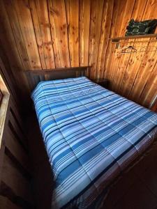 a bed in a cabin with a wooden wall at •Cabañas Patagonia• in Puerto Montt