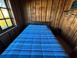 Cama en una cabaña de madera con colchón azul en •Cabañas Patagonia•, en Puerto Montt