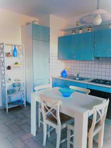 una cocina con armarios azules y una mesa y sillas blancas. en Borgo San Savino, en San Savino