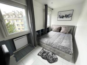 een kleine slaapkamer met een bed en een raam bij Élégant appartement, véranda cosy in Poissy