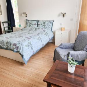 a bedroom with a bed and a chair and a table at Nara Seaside Retreat in Cultra