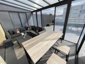 een balkon met een houten tafel en een bank bij Élégant appartement, véranda cosy in Poissy