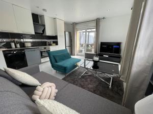 een woonkamer met een bank en een blauwe stoel bij Élégant appartement, véranda cosy in Poissy