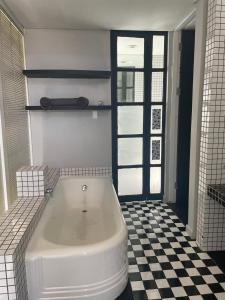 a white tub in a bathroom with a checkered floor at See You There Accommodation in Centurion
