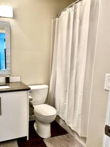 ein Bad mit einem WC und einem weißen Duschvorhang in der Unterkunft Modern & Luxurious Private Suite in Regina in Regina