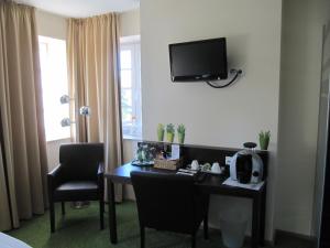 Zimmer mit einem Schreibtisch und einem TV an der Wand in der Unterkunft Hotel Stadt Steinheim in Steinheim