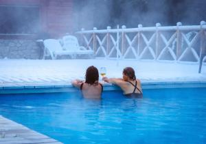 dwie kobiety w basenie z kieliszkiem wina w obiekcie ONA Apart Hotel and Spa w mieście Villa La Angostura