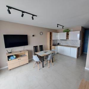a living room with a dining room table and a tv at Baltic Garden apartament dwupoziomowy 56 m² in Sztutowo