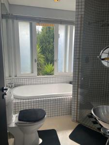 a bathroom with a tub and a toilet with a window at See You There Accommodation in Centurion