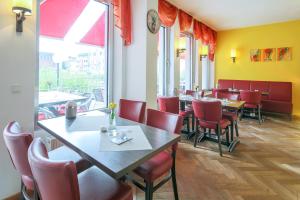Hotel Saarlouis am kleinen Markt في سارلويس: غرفة طعام مع طاولات وكراسي حمراء