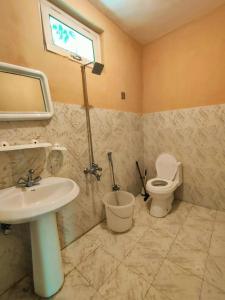 uma casa de banho com um lavatório, um WC e uma janela. em Trout Villa em Skardu