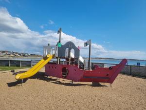 a playground with a slide on the beach at Apelvikens Camping & Cottages in Varberg