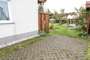 un jardín con una pasarela de piedra junto a una casa en Ferienwohnung Gustel, en Freest