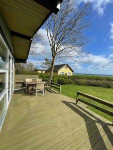 una terraza de madera con mesa y bancos en una casa en Summer House At Hvidbjerg Beach With Sea View en Børkop