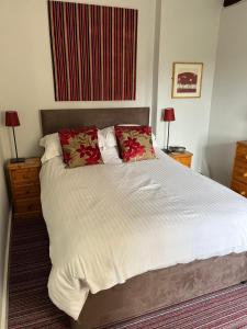 a bedroom with a large white bed with red pillows at Wellcroft in Buckinghamshire +13 photos