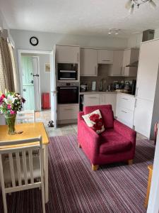 a living room with a red chair and a kitchen at Wellcroft in Buckinghamshire