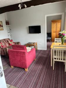 a living room with a red couch and a table at Wellcroft in Buckinghamshire