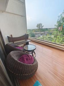 balkon z 2 krzesłami, stołem i oknem w obiekcie Quality Hospitality Services w mieście Pune