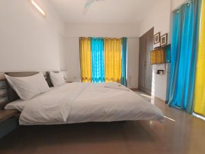 um quarto com uma cama grande com cortinas azuis e amarelas em Quality Hospitality Services em Pune