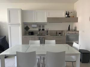 een witte keuken met een witte tafel en stoelen bij Riva House in Riva del Garda