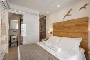 - une chambre avec un lit blanc et une tête de lit en bois dans l'établissement WePuglia - Vista Cattedrale, à Monopoli