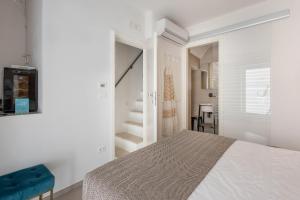 a white bedroom with a bed and a staircase at WePuglia - Vista Cattedrale in Monopoli