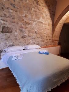 een wit bed in een kamer met een stenen muur bij "Il Pollaio" guests house in Panicale