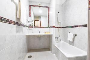 a bathroom with a sink and a tub and a mirror at Hotel Pozo del Duque II in Zahara de los Atunes