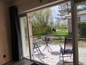 a sliding glass door to a patio with a table and chairs at Strandhuisje EVA, dicht bij zee in Callantsoog