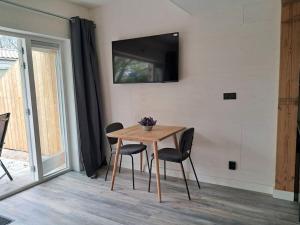 a dining room table with chairs and a television on a wall at Strandhuisje EVA, dicht bij zee in Callantsoog