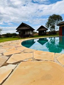 a swimming pool with two huts in the background at The Lookout in Naivasha