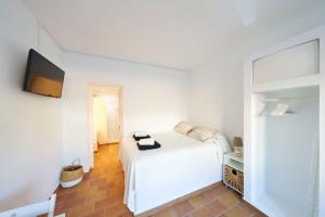 a white bedroom with a bed and a flat screen tv at Lirondo in San José