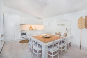 eine weiße Küche mit einem Holztisch und weißen Stühlen in der Unterkunft Casa Blanca in Selva
