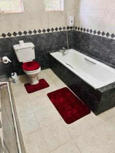 a bathroom with a tub and a toilet with red mats at The Lookout in Naivasha