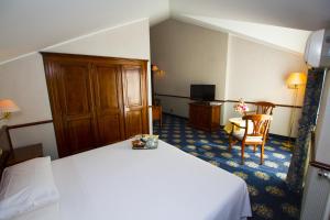 a hotel room with a white bed and a chair at Hotel De La Ville in Saint Vincent +20 photos
