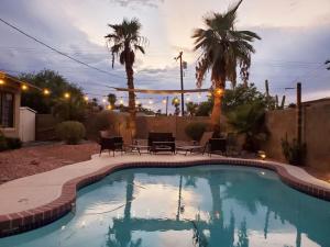 a swimming pool in a yard with chairs and palm trees at Palm house - Phoenix Home with renovated Pool and String Lights in Phoenix