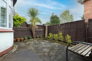 a privacy fence with a bench and a palm tree at Beautiful & comfortable home in Stockton-on-Tees