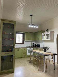 a kitchen with green cabinets and a table and chairs at Apartment Nina Holidays in Paralia Sikias